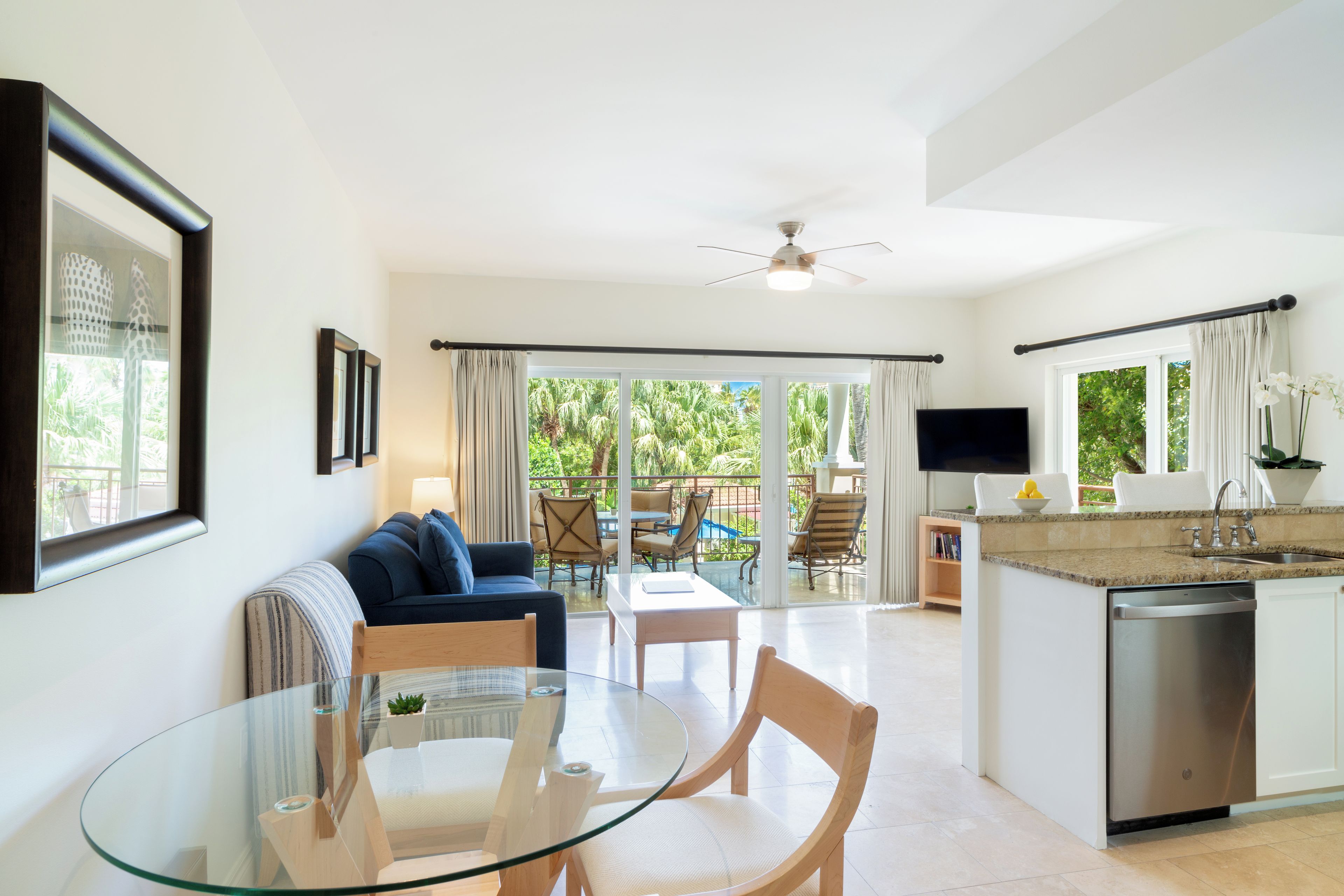 Una cocina moderna con una mesa de comedor de vidrio, lavavajillas integrado y vistas al exterior.
