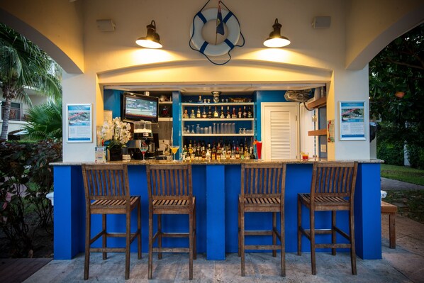 An outdoor bar area with a blue counter, wooden chairs, and a life preserver decoration on the ceiling. - Villa del Mar (Providenciales)