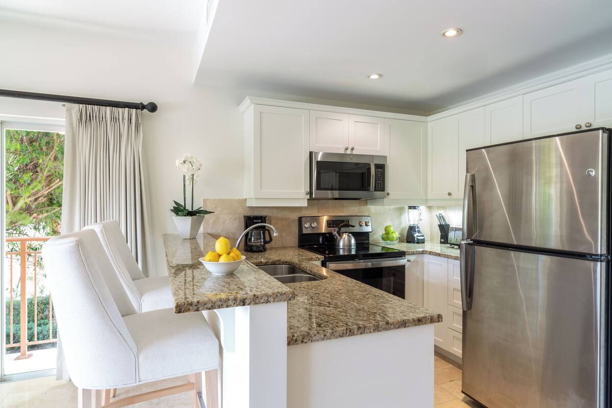 A modern kitchen with white cabinets, stainless steel appliances, and a granite countertop.