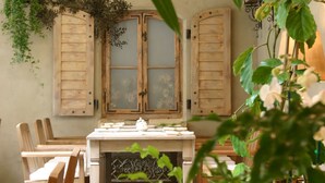 A rustic dining area with wooden furniture, a table set for a meal, and a window with shutters. - Art Hotel (Wroclaw)