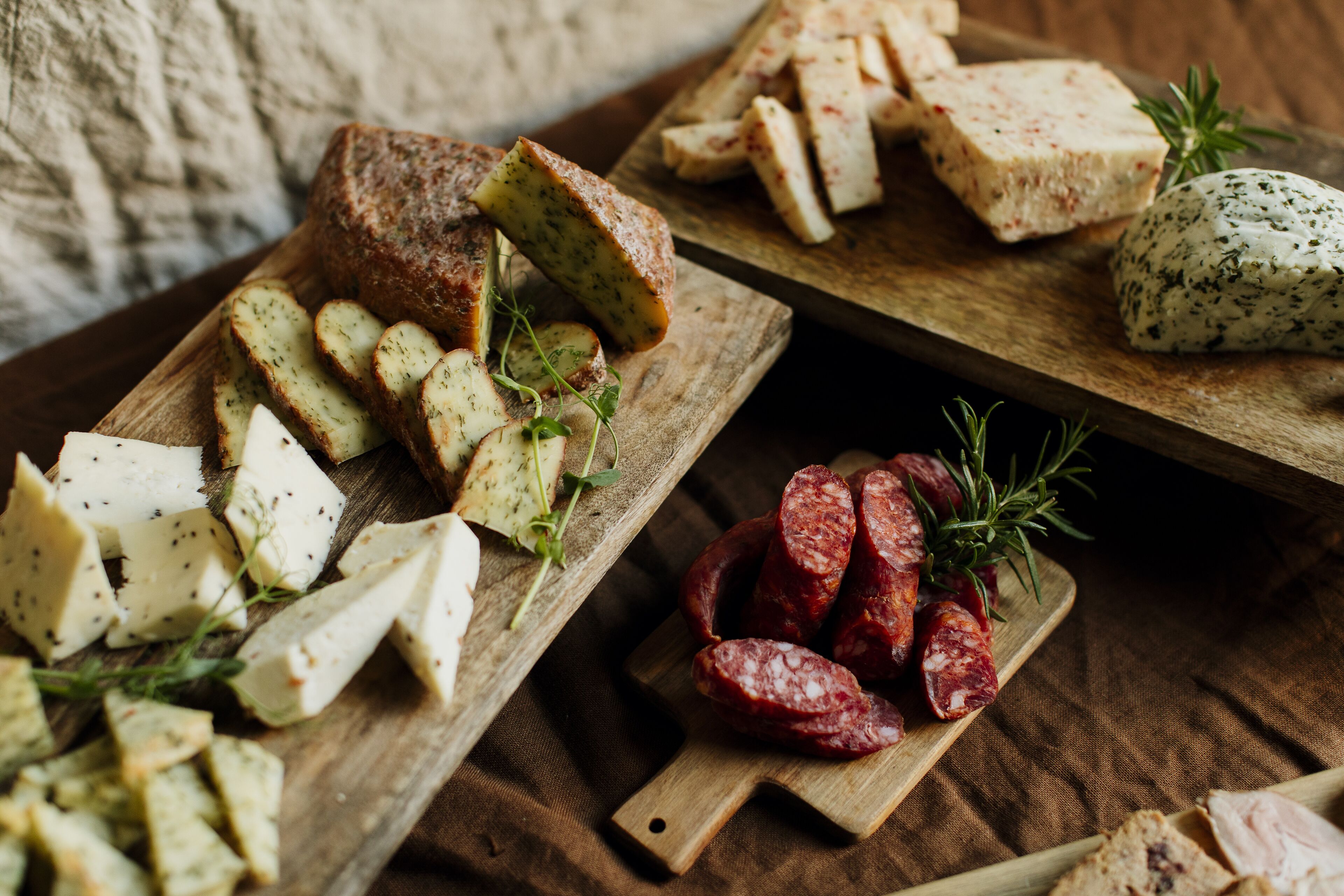 A wooden board with various cheeses, sliced bread, and cured meats.