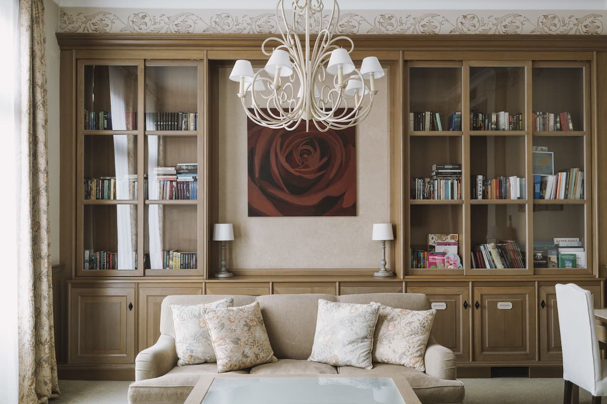 Un salón con un sofá color beige, una mesa de centro de vidrio y una amplia estantería llena de libros.