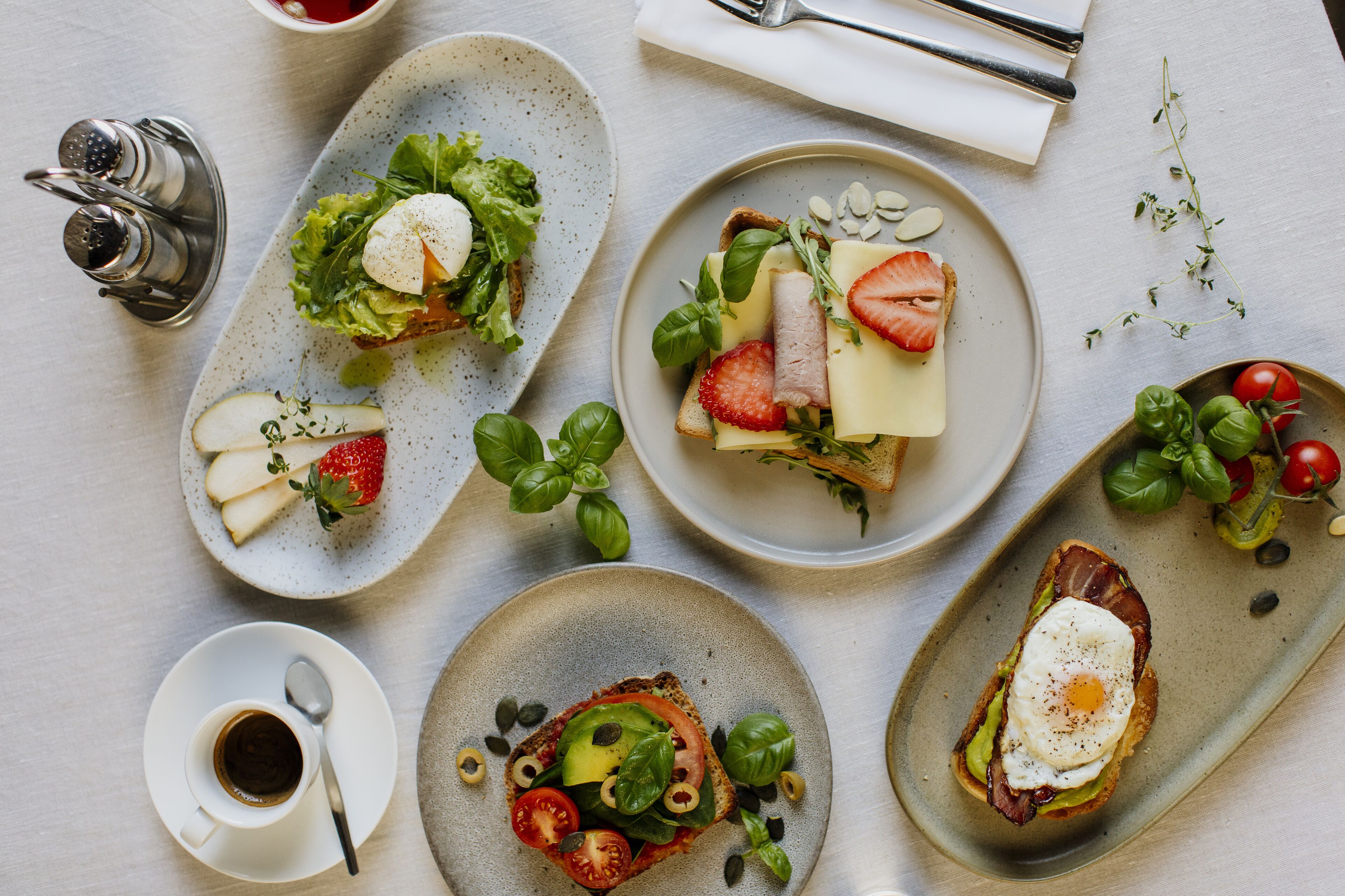 Una mesa con tres platos de comida, una taza de café y un salero y pimentero.