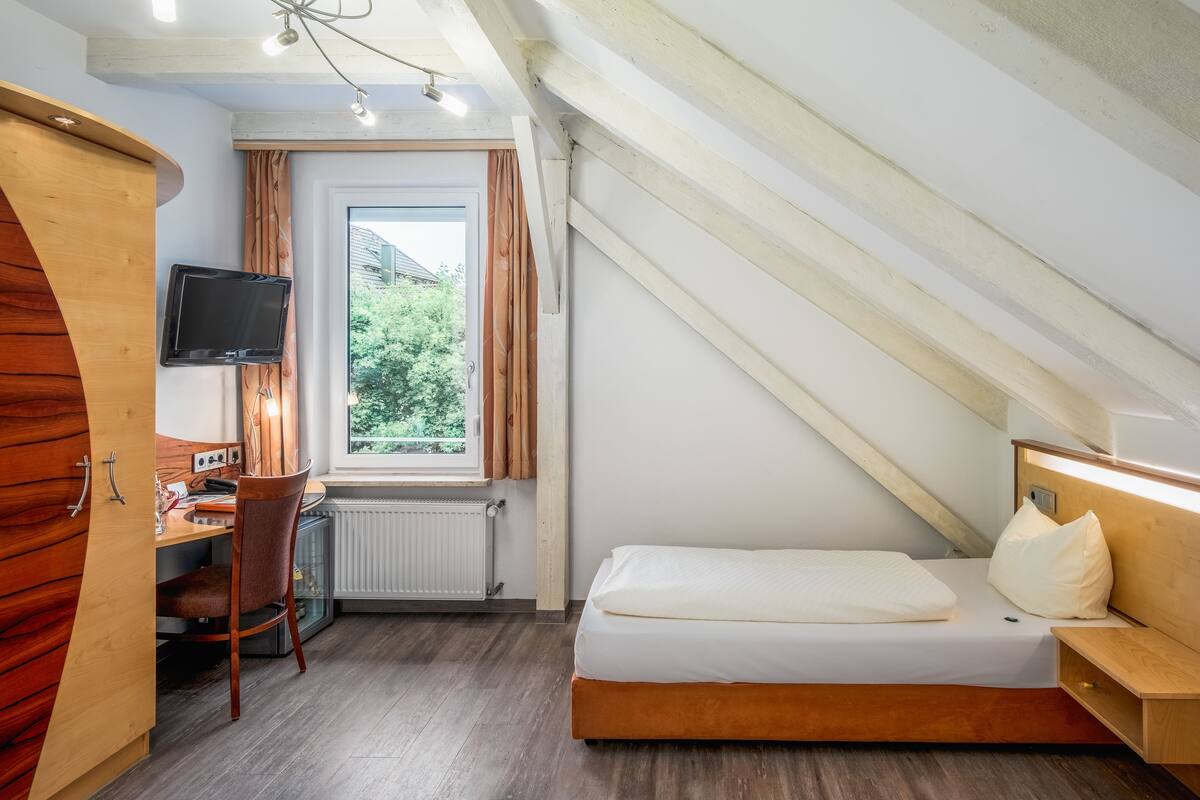 Une chambre à coucher de taille réduite, comprenant un lit, un bureau et un téléviseur.