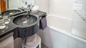 Un bagno moderno con un lavandino in granito, uno specchio, un soffione a mano e una vasca da bagno.
