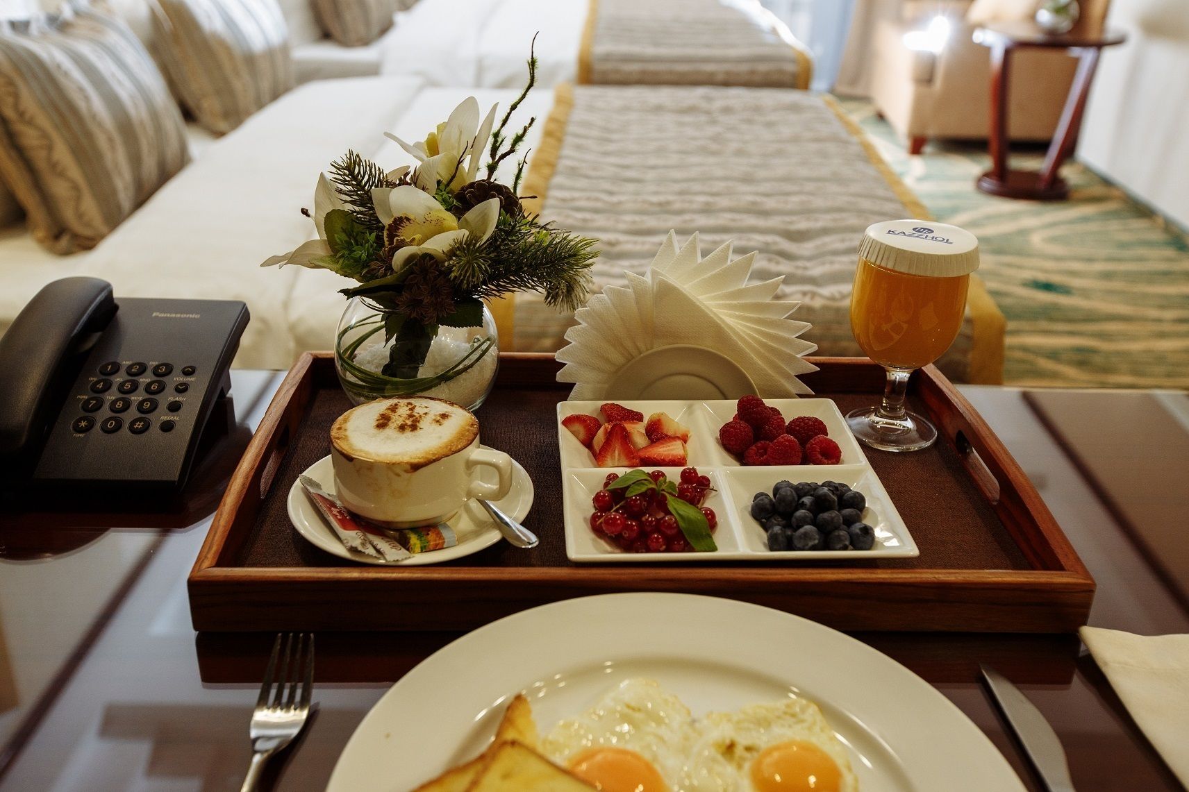 Un vassoio per la colazione con una tazza di caffè, un bicchiere di succo d'arancia e un piatto con fragole, lamponi e mirtilli.