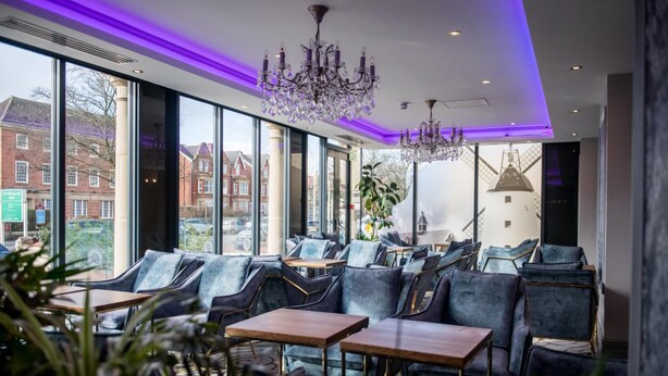 Een modern interieur met zithoeken, grote ramen en een kroonluchter.