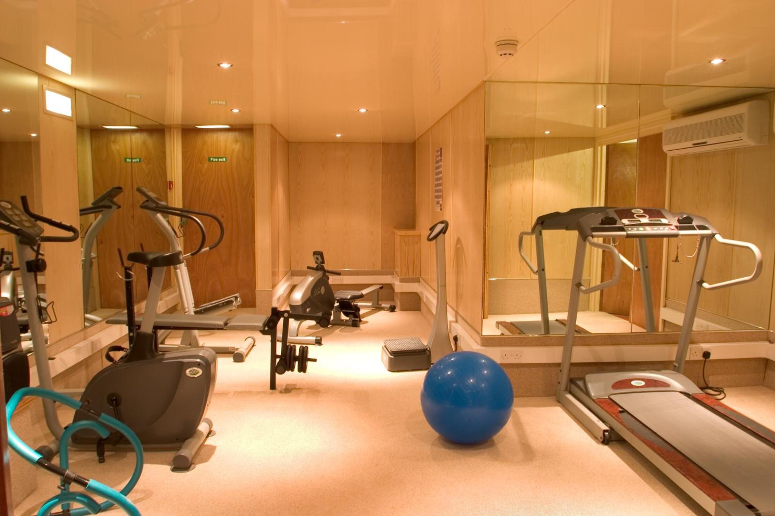 A hotel fitness room with exercise equipment, including treadmills, an elliptical, and a stationary bike.