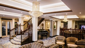Een statig atrium met een piano, een trap en comfortabele zithoeken.