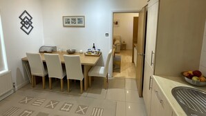 Una cocina moderna con comedor, que incluye una mesa de madera, sillas blancas y un horno empotrado.