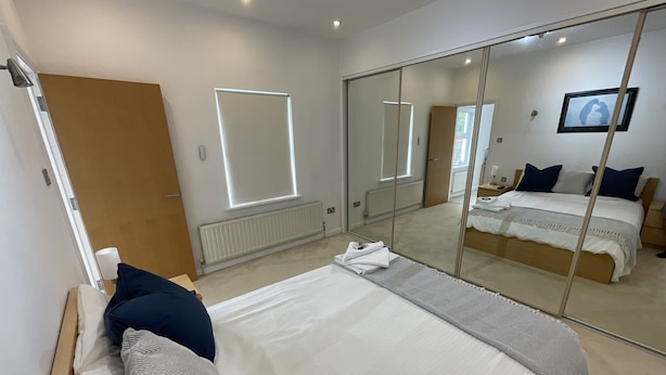 Un dormitorio moderno con una cama grande, un armario, un espejo y una mesita de noche.