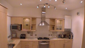 Cocina moderna con una isla central, microondas integrado, horno y campana extractora de acero inoxidable.