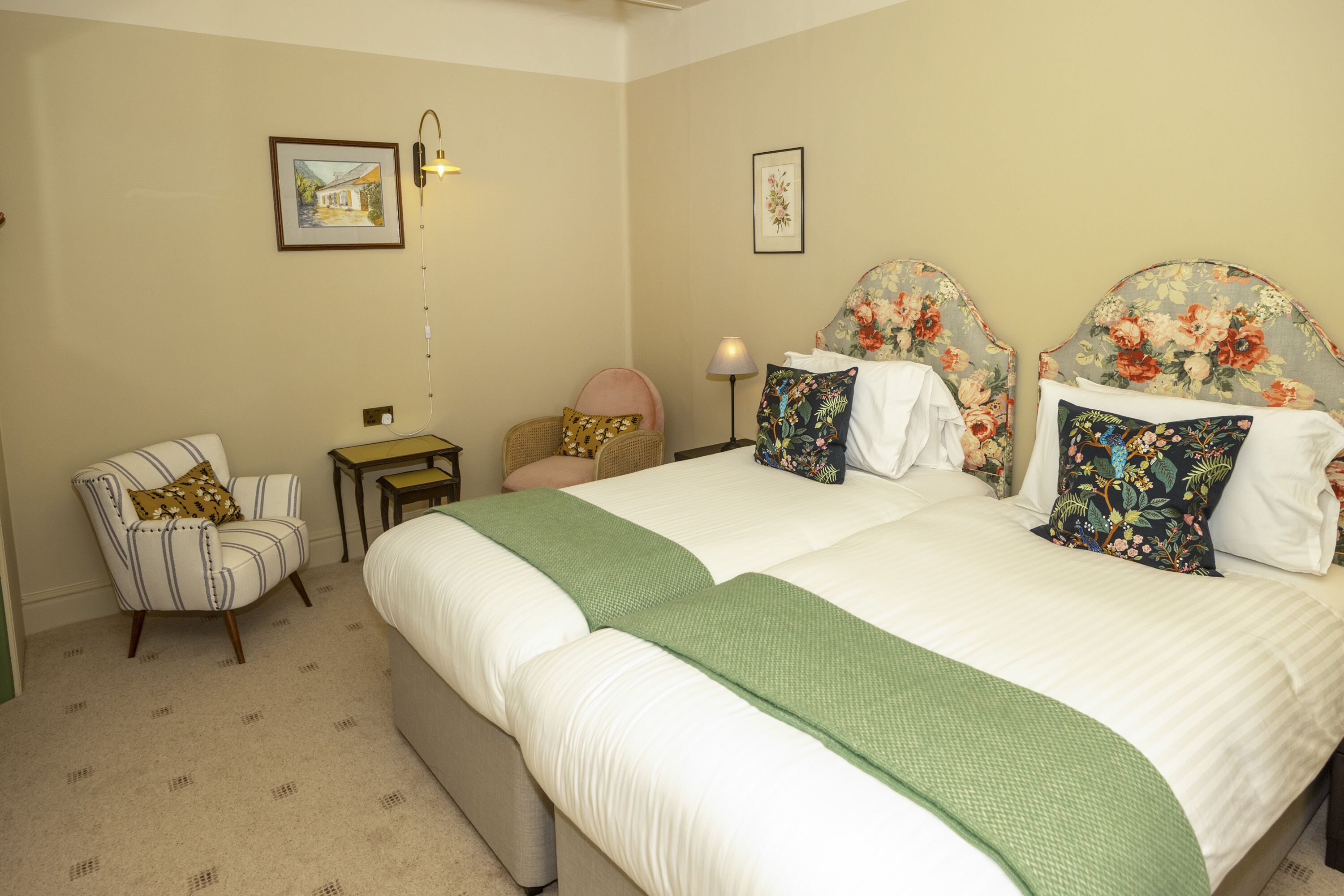 A bedroom with a large bed, a chair, a nightstand, and two wall-mounted lamps.
