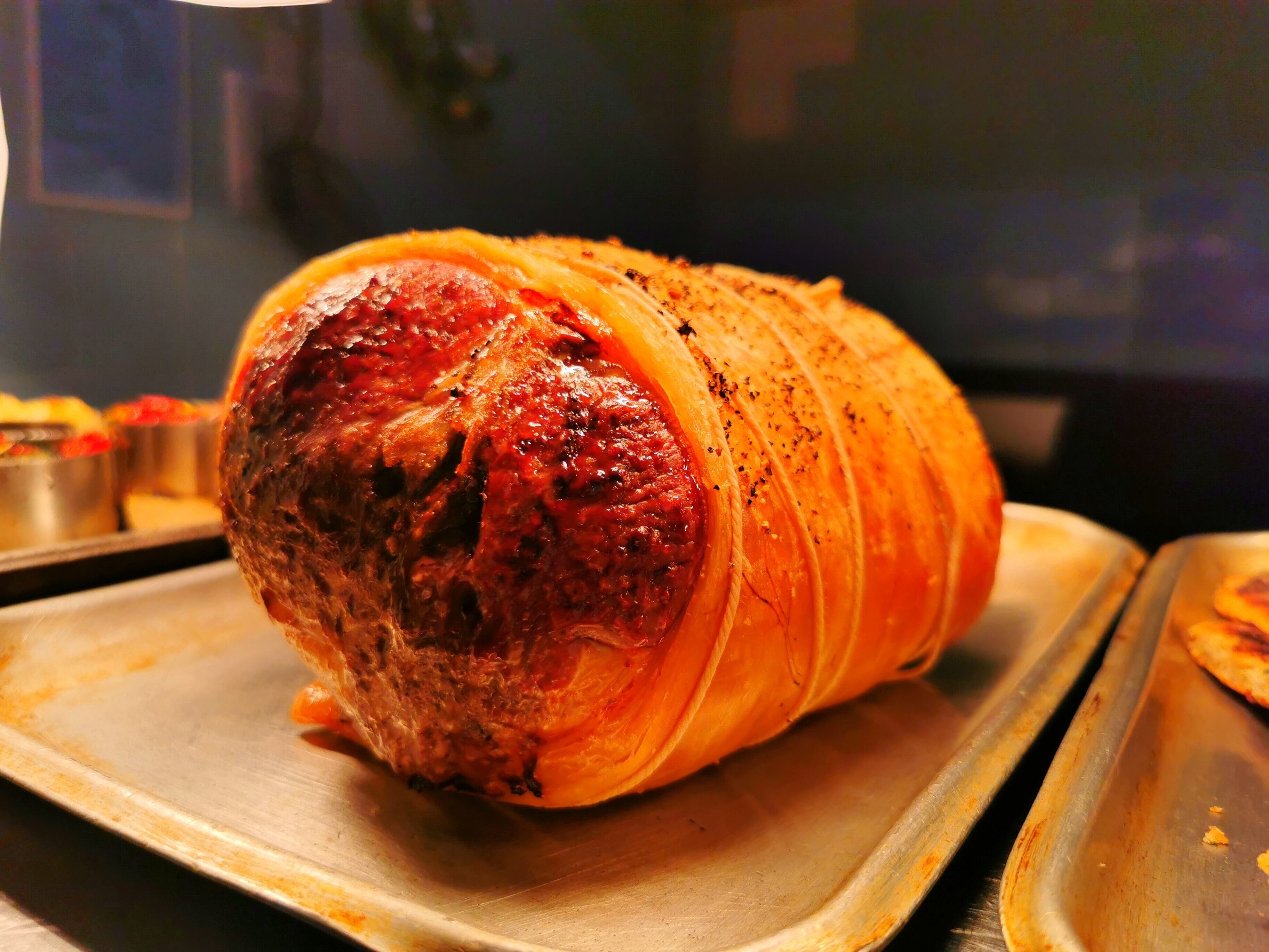 A roasted ham on a metal tray.