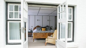 A bedroom with a wooden bed, a chair, and a window with curtains. - Mill End Hotel (Newton Abbot)