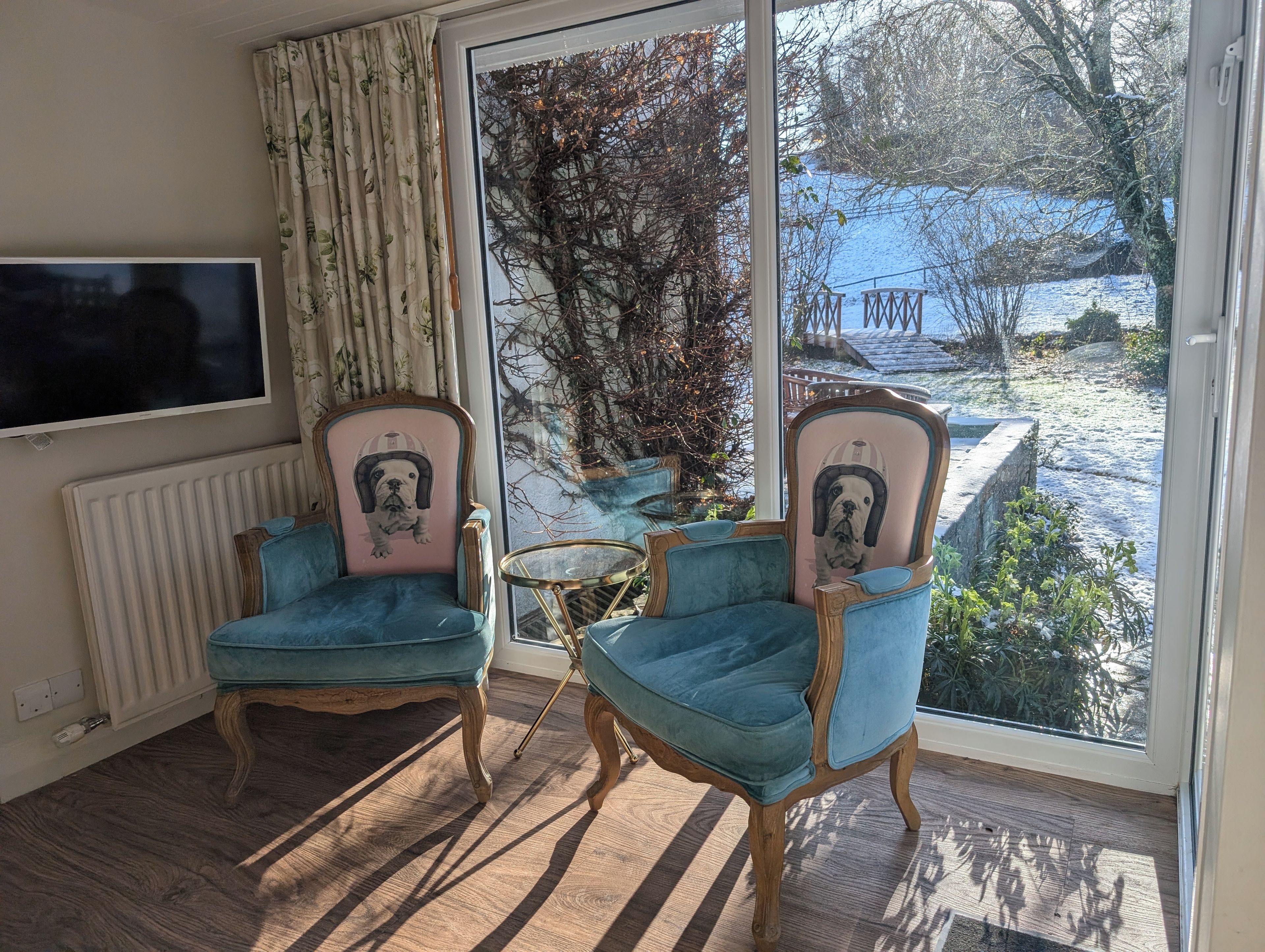 A room with two armchairs, a television, and a view of a snowy landscape.