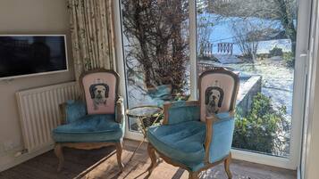 A room with two armchairs, a television, and a view of a snowy landscape.