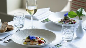 A dining table set with plates of food, glasses of water, and a white vase with a plant. - Mill End Hotel (Newton Abbot)
