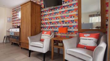 A room with two armchairs, a wooden cabinet, and a wall with colorful book covers.