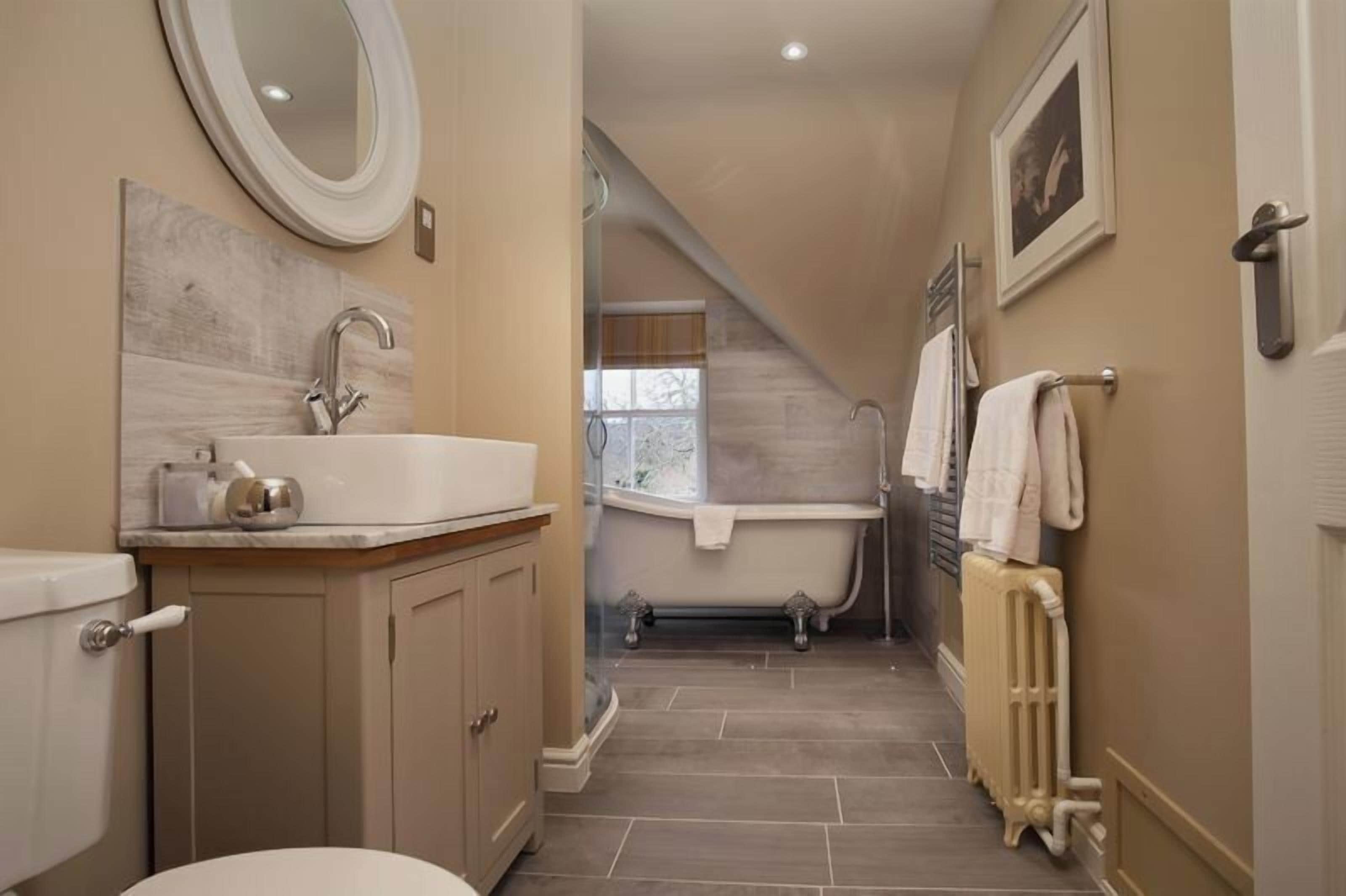 A narrow bathroom with a sink, mirror, and bathtub.