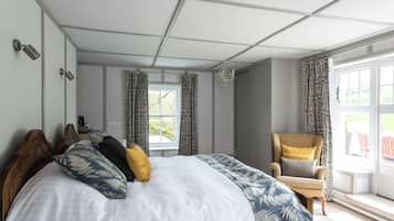 A bedroom with a large bed, a chair, a window, and a view of the outdoors.