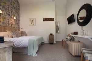 Un dormitorio con cama, mesita de noche, cómoda y televisor en la pared.