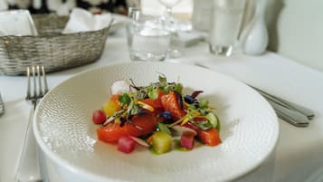 A white textured plate with a colorful salad, a fork, and a knife on a table.