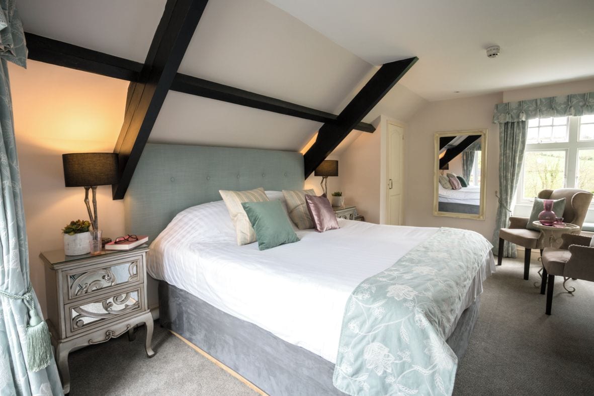 A bedroom with a large bed, bedside tables, a chair, and a window with curtains.