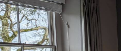 Une chambre d’hôtel avec un lit, une fenêtre donnant sur des arbres et une table de chevet avec des serviettes.