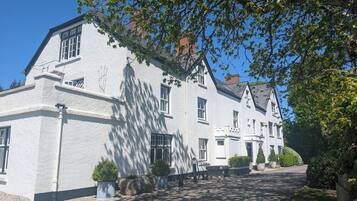 A white building with multiple windows and a paved driveway.