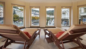 Une pièce comprenant quatre fauteuils en bois et une grande fenêtre donnant sur un paysage urbain.