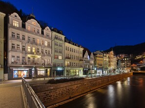 A waterfront hotel with multiple stories, balconies, and a river in the foreground. - EA Hotel Elefant (Karlovy Vary)
