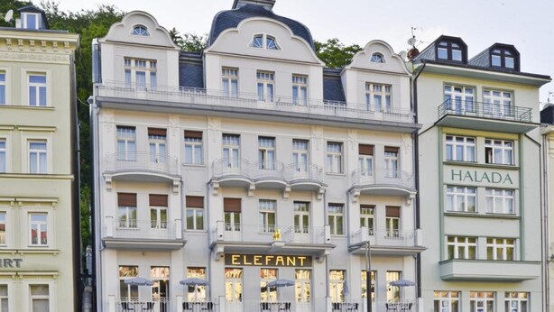 Un immeuble à plusieurs étages, dont le rez-de-chaussée est occupé par un grand magasin appelé « ELEFANT ».