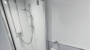 A glass-enclosed shower with a handheld showerhead and a wall-mounted faucet. - Kings Knoll Hotel (Oban)