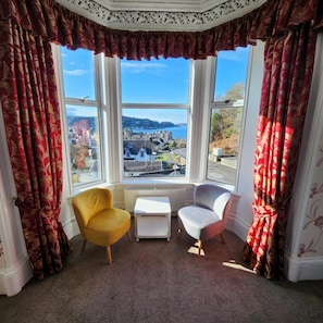 A room with a bay window, two chairs, a small table, and a radiator. - Kings Knoll Hotel (Oban)