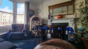 A living room with a fireplace, a large window, a clock, and a bookshelf. - Marine View (Brighton)