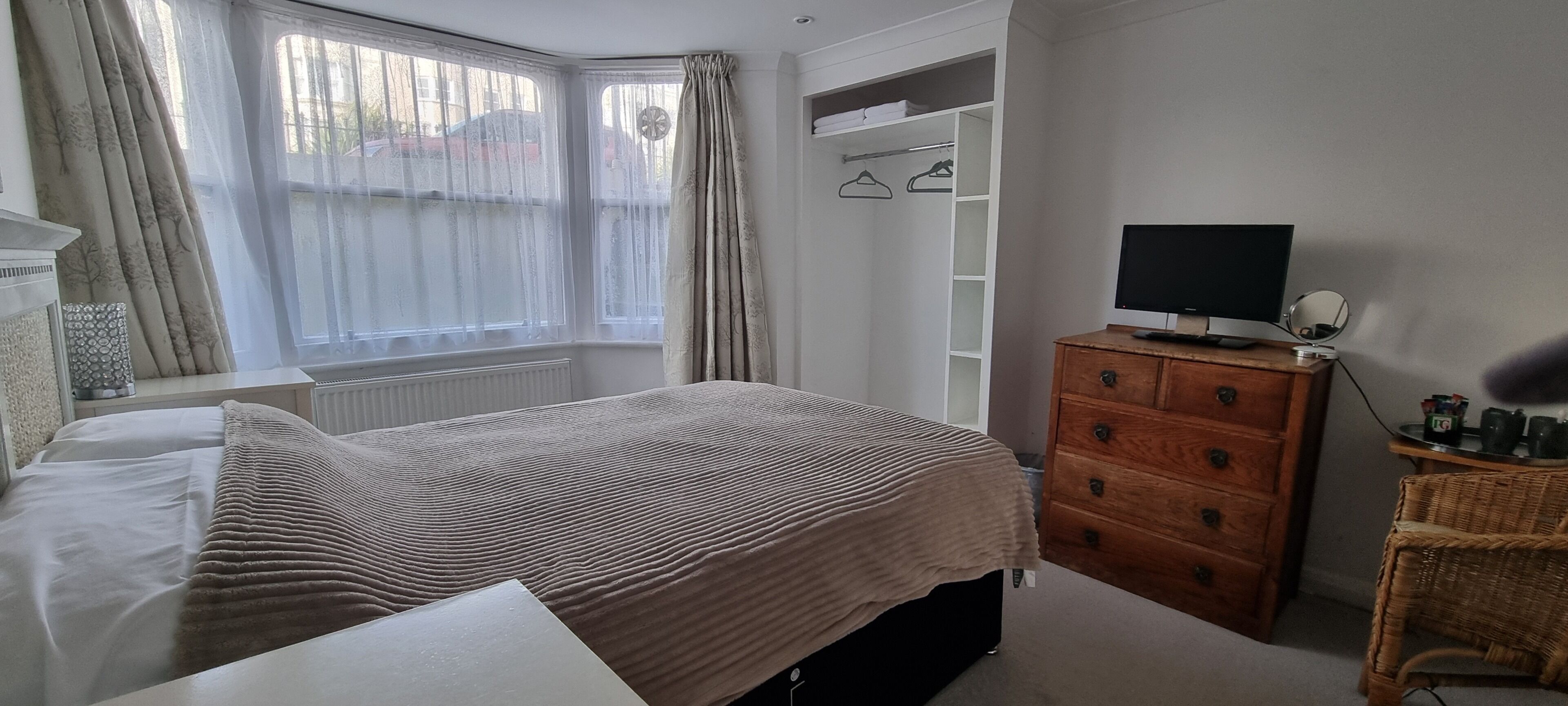 A bedroom with a bed, a dresser, a television, and a wardrobe.