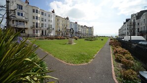 A pathway leading to a row of terraced houses with a grassy area in the middle. - Marine View (Brighton)