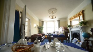 A dining room with a table set for breakfast, a fireplace, and a large mirror above it. - Marine View (Brighton)