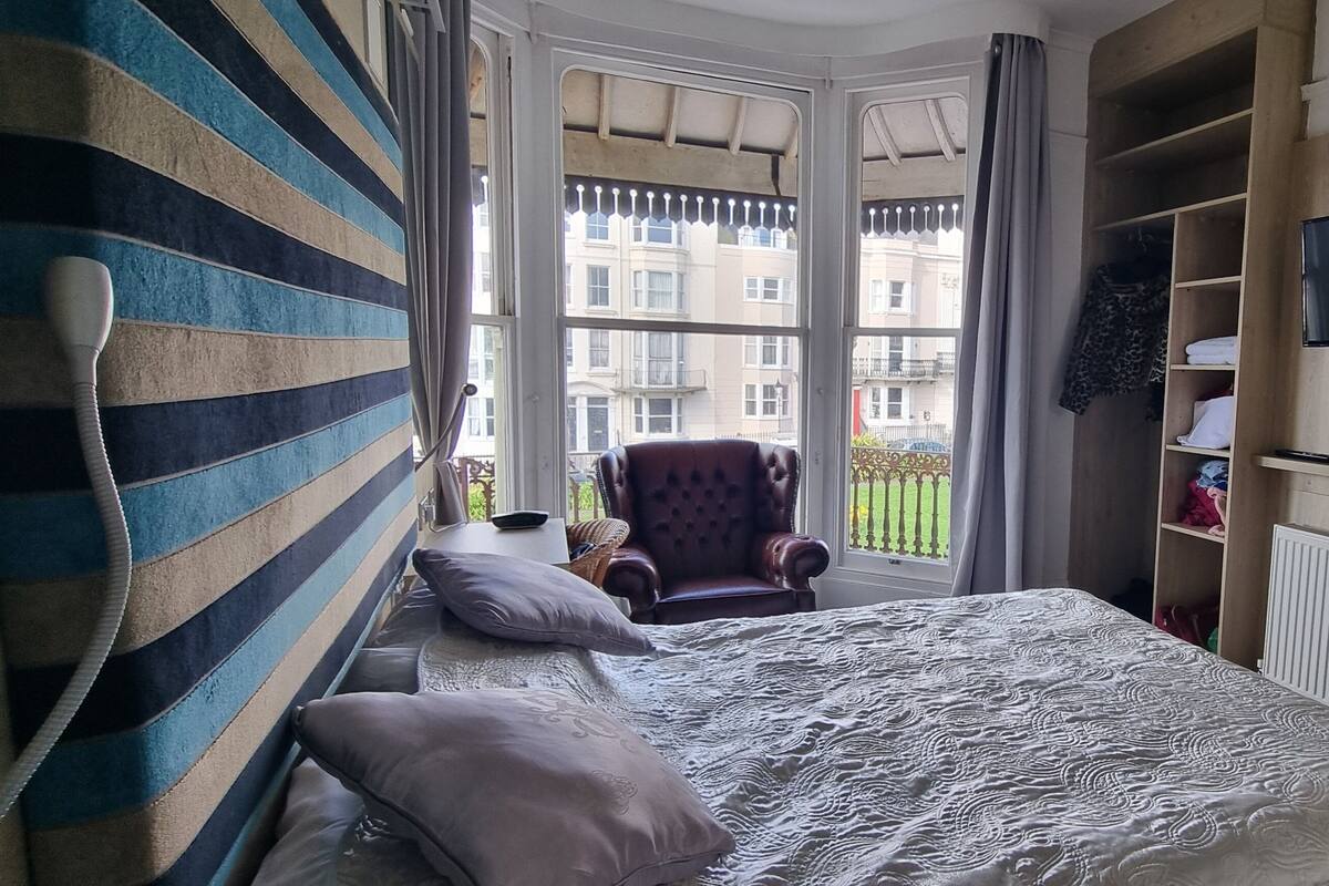 A bedroom with a bed, a chair, a TV, and a wardrobe.