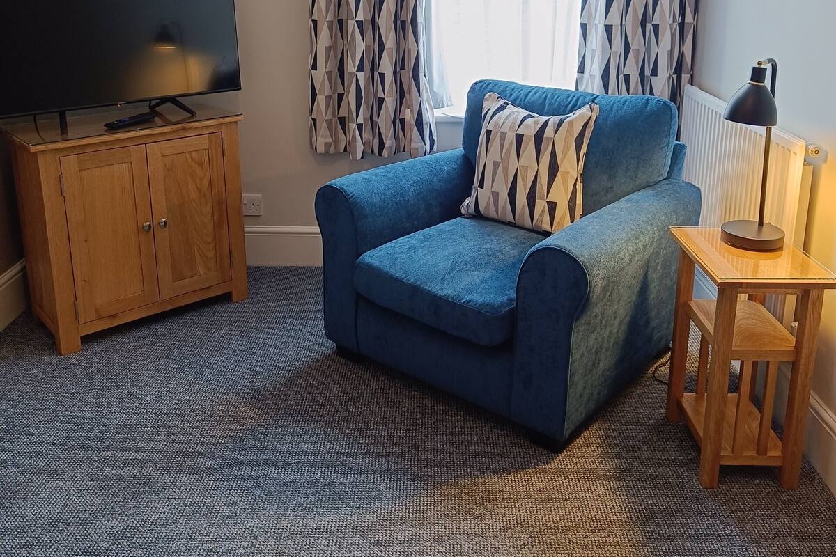 A living room with a blue sofa, a wooden cabinet, a TV, and a lamp.