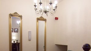 A hotel room with two mirrors, a chandelier, a fire exit sign, and a red object on the wall. - Powys Lodge (Scarborough)