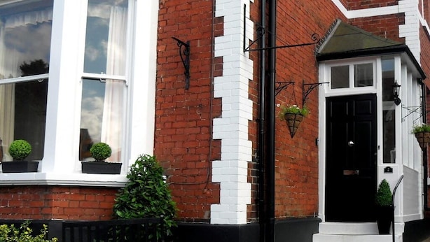 A corner building with a white window, black door, and a brick facade. - Powys Lodge (Scarborough)