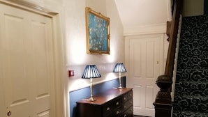 A hallway with a dark wooden dresser, two lamps, and a framed painting on the wall. - Powys Lodge (Scarborough)