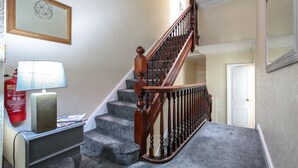 Una escalera con barandilla de madera y peldaños alfombrados.