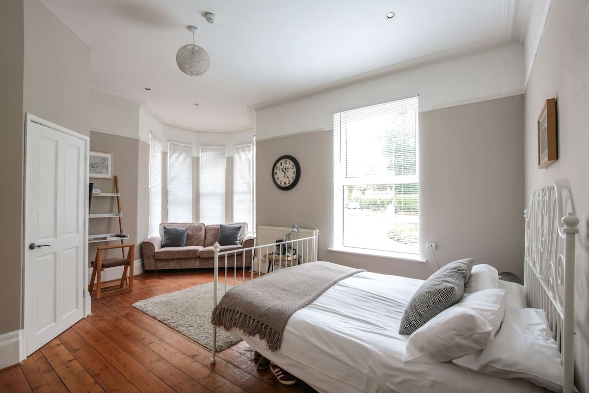 A bedroom with a bed, a window, a radiator, and a door.