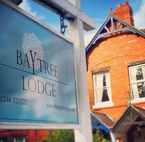 A sign for Bay Tree Lodge with a contact number and website URL.
