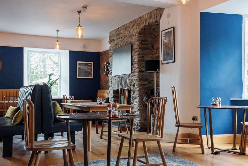 Un restaurante acogedor con mobiliario de madera, paredes de piedra e iluminación colgante.