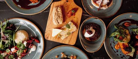 A variety of dishes on plates and a wooden board, suggesting a dining setting.