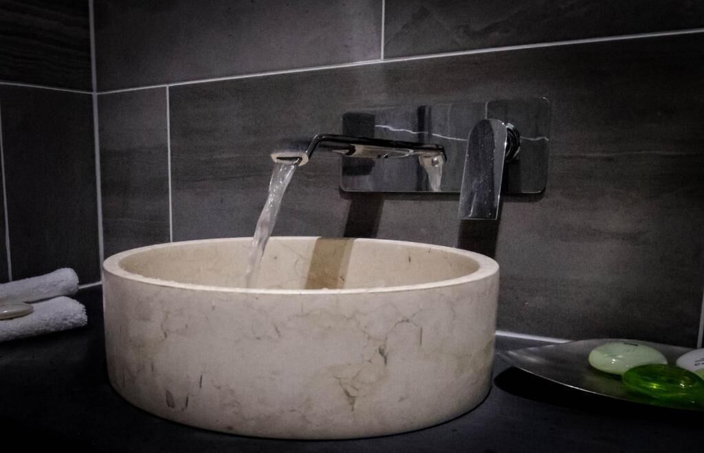 A bathroom with a marble sink, a faucet, and a mirror.